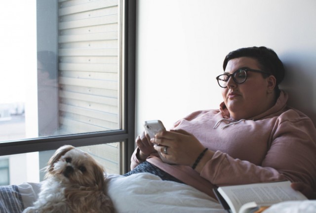 woman-on-phone-in-bed-small-dog-with-her-850