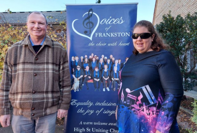 Jenni and Niall standing in front of the Voices of Frankston banner at the Frankston Uniting Church