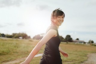 woman jogging into distance turns back and smiles