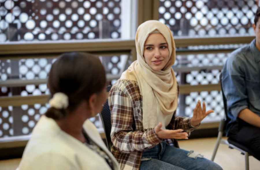 Young girl wearing a hijab talking to a group