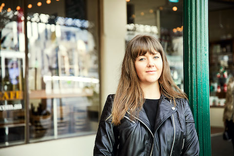 person looking relaxed standing in front of cafe wearing a leather jacket
