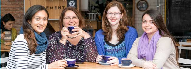 Four welcoming looking women sitting around a coffee table